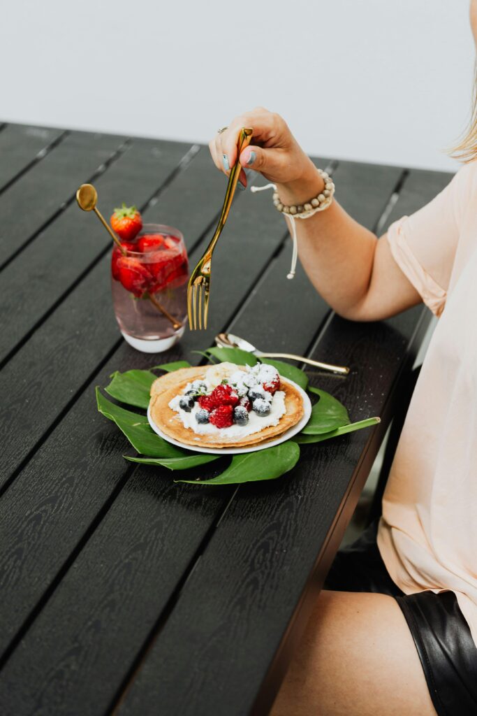 Une femme attablée en terrasse déguste un dessert